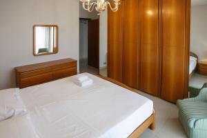 1 dormitorio con 1 cama blanca grande y armario de madera en Ginevra Apartment, en Cefalú