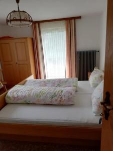 uma cama com duas almofadas com uma janela em Haus Marion em Jerzens