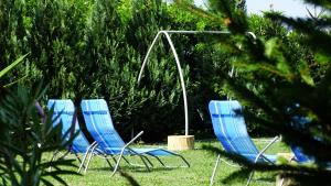 drei blaue Gartenstühle sitzen im Gras in der Unterkunft Rider Beach in Balatonszemes