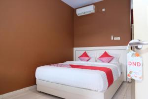 una camera da letto con un letto con cuscini rossi e bianchi di SUPER OYO 811 Mars Kost Syariah a Jambi