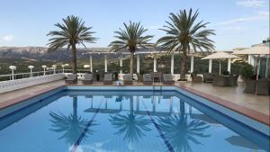 a swimming pool with palm trees in the background at Castri Village Hotel in Palekastron