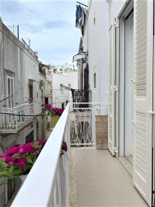 einen Balkon mit rosa Blumen auf einem weißen Gebäude in der Unterkunft Le Petunie in Ostuni