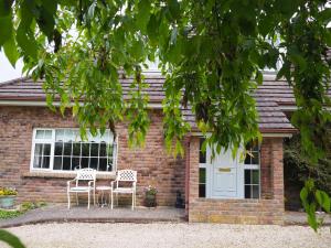 una casa de ladrillo con una mesa y sillas delante de ella en Inglewood Lodge B&B en Naas