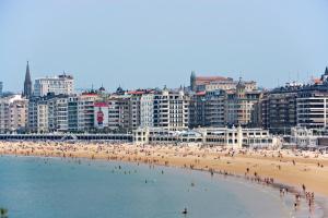 a group of people on a beach in front of a city at Hotel Niza in Donostia-San Sebastián