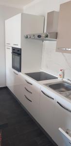 a white kitchen with a sink and a microwave at Matušanka Apartment in Rab