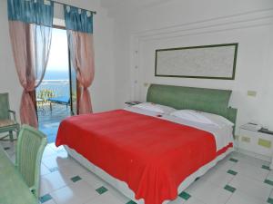 1 dormitorio con cama roja y vistas al océano en Hotel Holiday, en Praiano