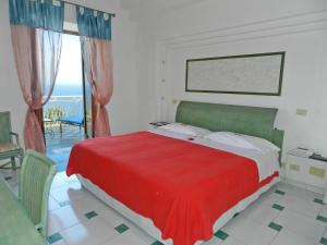 una camera con letto rosso e vista sull'oceano di Hotel Holiday a Praiano