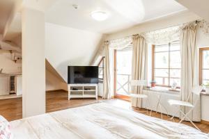 a white bedroom with a bed and a television at Karlamuiza Country Hotel in Kārļi