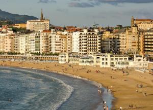 a group of people on a beach with buildings at Hotel Niza in Donostia-San Sebastián