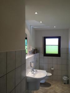 La salle de bains blanche est pourvue d'un lavabo et d'une fenêtre. dans l'établissement Landhaus Hotel Göke, à Hövelhof