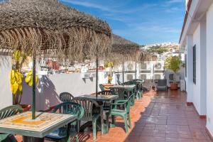 un patio extérieur avec des tables, des chaises et des parasols dans l'établissement Apartamentos El Cenachero, à Malaga