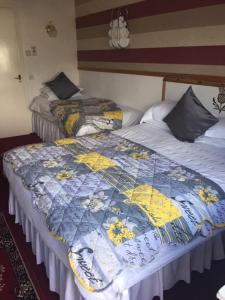 two beds in a room with a quilt on them at The Thistle Inn in Stranraer