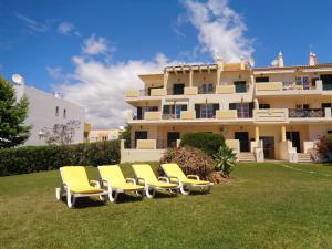 a group of yellow chairs in front of a building at Apartamento Citimar in Vilamoura