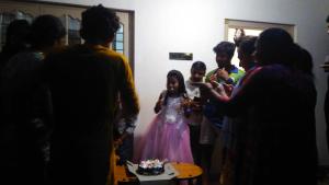 a group of people standing around a little girl in front of a cake at Leeland Munnar in Munnar