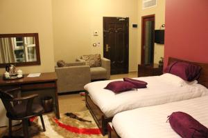 a bedroom with two beds and a desk and a chair at Kanaan Group Hotel in Baalbeck