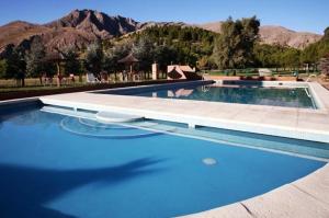 uma grande piscina azul com montanhas ao fundo em El Mirador Complejo Turístico em Villa Ventana