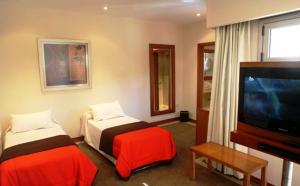 um quarto de hotel com duas camas e uma televisão de ecrã plano em El Mirador Complejo Turístico em Villa Ventana