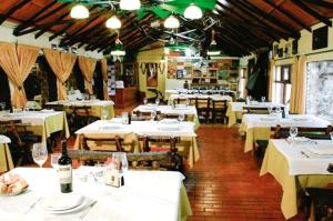 um restaurante com mesas brancas e cadeiras com garrafas de vinho em El Mirador Complejo Turístico em Villa Ventana