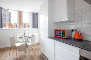 une cuisine avec une table et un four micro-ondes rouge dans l'établissement Leicester Luxury Apartment - S05, à Leicester