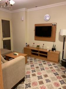 Altelal Apartment في مكة المكرمة: غرفة معيشة مع أريكة وتلفزيون بشاشة مسطحة