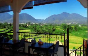 a balcony with two tables and a view of mountains at Hotel FX72 Ruteng in Ruteng
