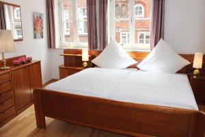 een slaapkamer met een bed met witte lakens en 2 ramen bij ALTSTADTGLÜCK - inklusive Privatparkplatz! in Lüneburg
