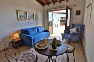 a living room with a blue couch and a table and chairs at Samareitidos Light Cottage in Anaphotia