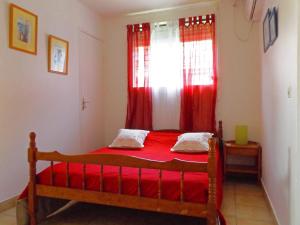 1 dormitorio con 1 cama con cortinas rojas y ventana en Résidence Cassin Nicol, en Terre-de-Haut