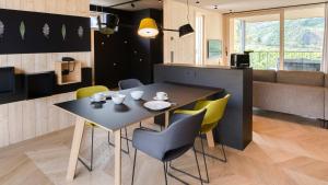 a dining room with a black table and yellow chairs at Cirna Gentle Luxury Lodges in Naturno