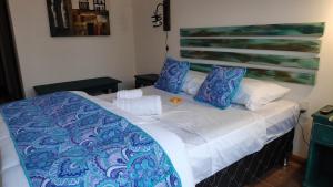 Cama con sábanas y almohadas azules y blancas en El Bodegón Hostal Boutique, en Punta del Diablo
