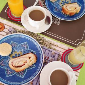 una mesa con platos de comida y tazas de café en El Bodegón Hostal Boutique, en Punta del Diablo
