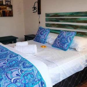 Cama con sábanas y almohadas azules y blancas en El Bodegón Hostal Boutique, en Punta del Diablo