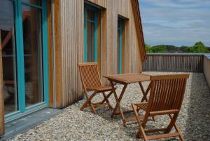 2 sedie e un tavolo in legno sul balcone di Ferienwohnung Passivhaus "Schöne Aussicht" a Georgensgmünd