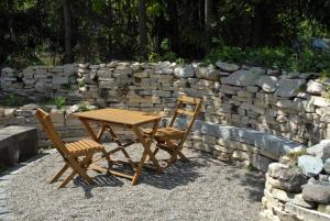 a wooden table and two chairs next to a stone wall at Ferienwohnung Passivhaus "Schöne Aussicht" in Georgensgmünd +14 photos