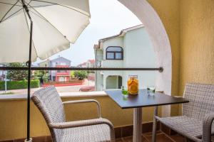 einen Tisch mit 2 Stühlen und einem Sonnenschirm auf dem Balkon in der Unterkunft Apartments TB in Porat