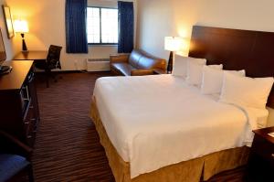 una habitación de hotel con una cama grande y una silla en Cobblestone Inn & Suites - Holstein, en Holstein