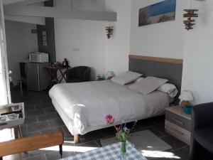 ein Schlafzimmer mit einem Bett und einem Tisch mit einer Blumenvase in der Unterkunft Les oyats in Le Crotoy
