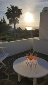 three wine glasses sitting on a table on a balcony at Naxos Beachvilla in Plaka