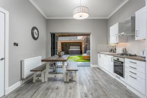 uma cozinha com armários brancos e uma mesa de madeira em The Alexander - Donnini Deluxe em Prestwick