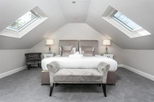 a bedroom with a white bed with a chair and windows at The Alexander - Donnini Deluxe in Prestwick