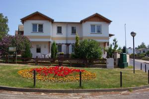 ein Haus mit einem Blumenbett davor in der Unterkunft Pension Voss in Ückeritz