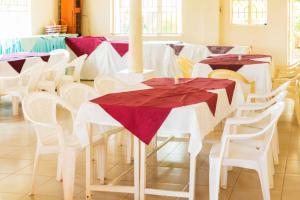 a dining room with white tables and white chairs at Meliva Guest House Mbarara in Mbarara