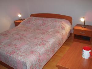 a bedroom with a bed and two night stands with lamps at Apartment Orbanić Cres in Cres