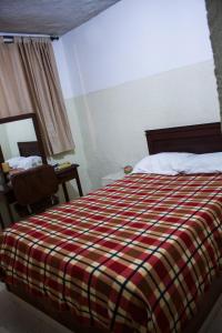 a bedroom with a bed with a checkered blanket at Hotel Pacifico in Palmira