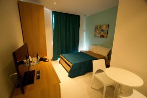 Mały pokój z łóżkiem, stołem i biurkiem w obiekcie Harbour Lodge w mieście Marsaxlokk