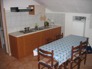 - une cuisine avec une table, un évier, une table et des chaises dans l'établissement Apartment Orbanić Cres, à Cres
