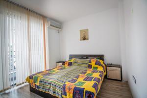 a bedroom with a bed with a colorful blanket at Cozy One-bedroom Apartment in Night Breeze in Burgas