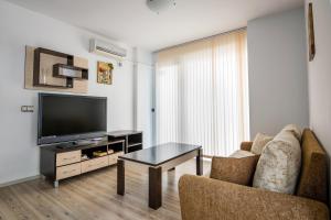 a living room with a tv and a couch and a table at Cozy One-bedroom Apartment in Night Breeze in Burgas
