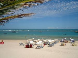 a beach with many chairs and umbrellas and the ocean at Pousada Brisa e Mar in Praia do Frances