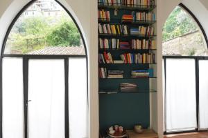 two windows in a room with a book shelf with books at Montalcino Loft in Montalcino